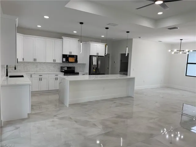 Kitchen featuring sink, white cabinetry, black appliances, and a center island