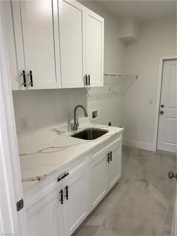 Washroom featuring cabinets, hookup for an electric dryer, hookup for a washing machine, and sink