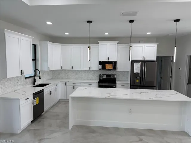 Kitchen with white cabinetry, a center island, decorative light fixtures, black appliances, and sink