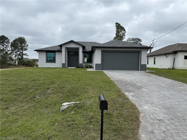 View of front facade featuring a front lawn and a garage