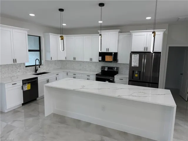 Kitchen with a kitchen island, pendant lighting, white cabinets, and black appliances