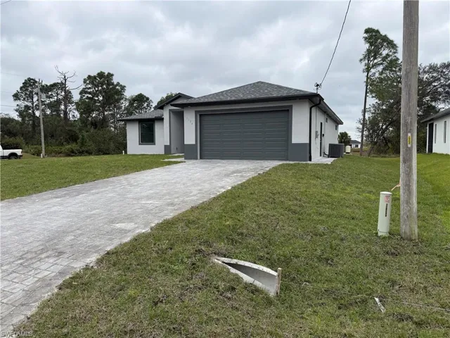 View of front of home with a front lawn, a garage, and central air condition unit