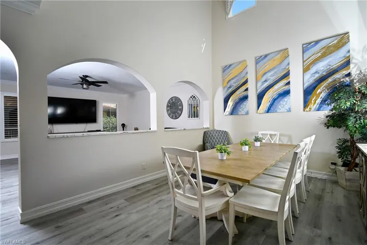 Dining area with crown molding, ceiling fan, hardwood / wood-style floors, and a towering ceiling