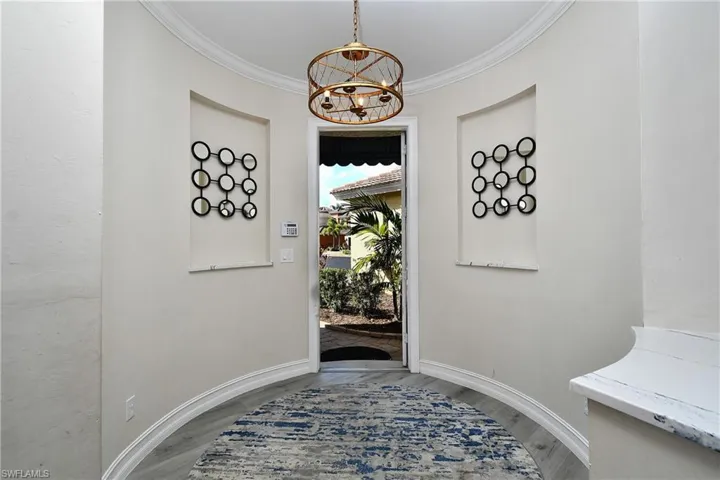 Foyer entrance with hardwood / wood-style flooring, ornamental molding, and a chandelier