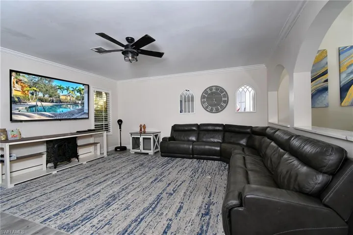 Living room with crown molding, wood-type flooring, and ceiling fan