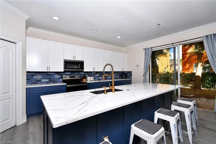 Kitchen featuring appliances with stainless steel finishes, sink, a center island with sink, and white cabinets