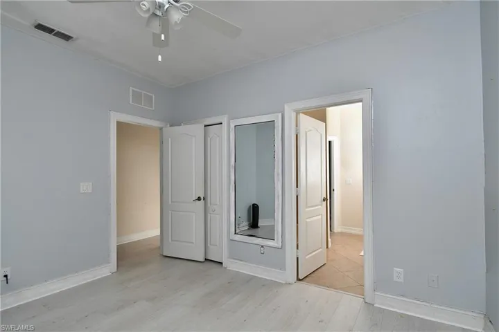 Bedroom with two closets, ceiling fan, and light hardwood / wood-style flooring