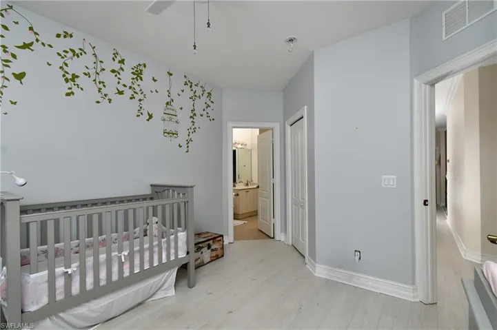 Bedroom with connected bathroom, a closet, ceiling fan, and light wood-type flooring