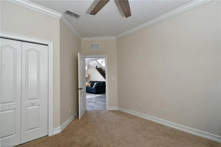 Bedroom featuring ceiling fan, light colored carpet, ornamental molding, and a closet