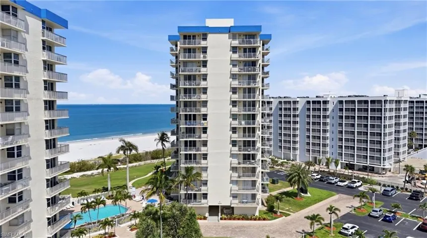 Mid-rise condominium complex with multiple balconies and a blue roofline - Virtually Edited Image