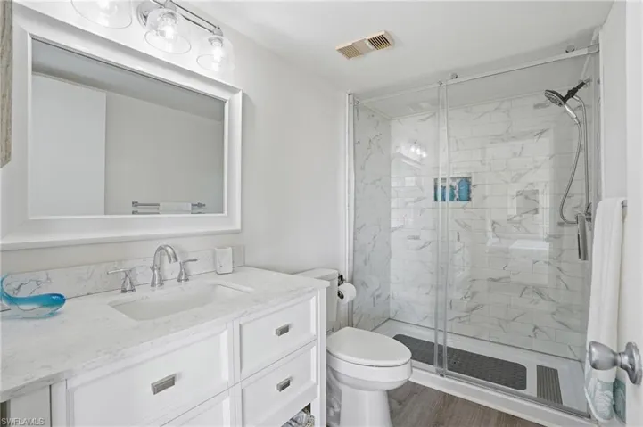 Modern bathroom featuring a white vanity with an integrated sink, a large framed mirror, and chrome fixtures - Virtually Edited Image