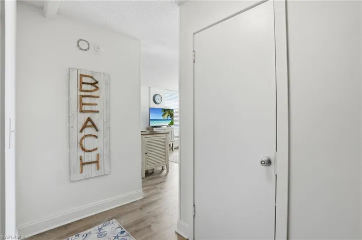 Entryway featuring light wood-finish flooring, white baseboards, and a white interior door with a chrome knob - Virtually Edited Image