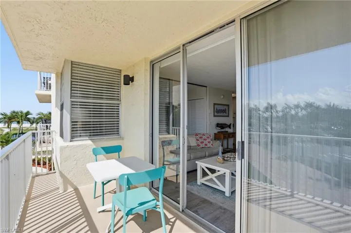 Outdoor balcony featuring a textured wall finish, white metal railing, and sliding glass doors - Virtually Edited Image