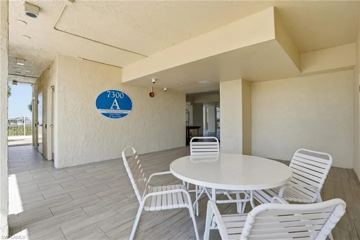 Covered outdoor patio area featuring light-toned stucco walls and plank-style tile flooring - Virtually Edited Image