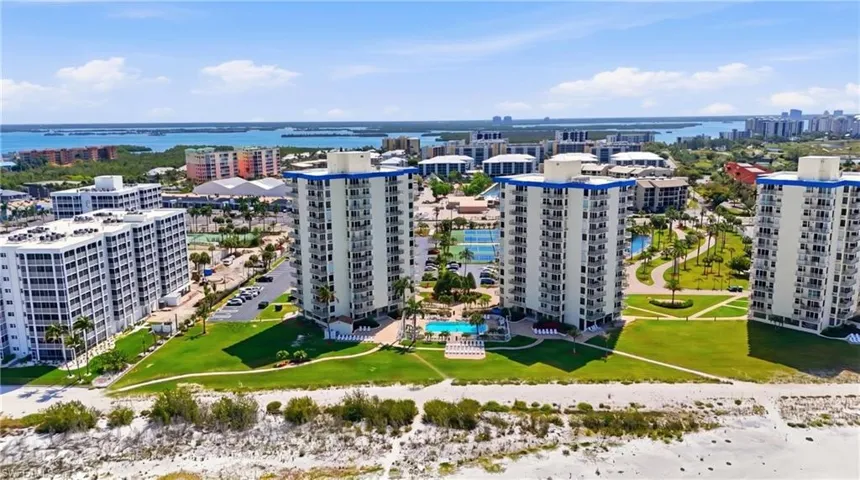 Multi-building complex featuring high-rise structures with private balconies, manicured green spaces, and a central swimming pool - Virtually Edited Image