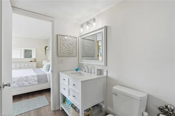 White vanity with integrated sink, chrome faucet, and framed mirror - Virtually Edited Image