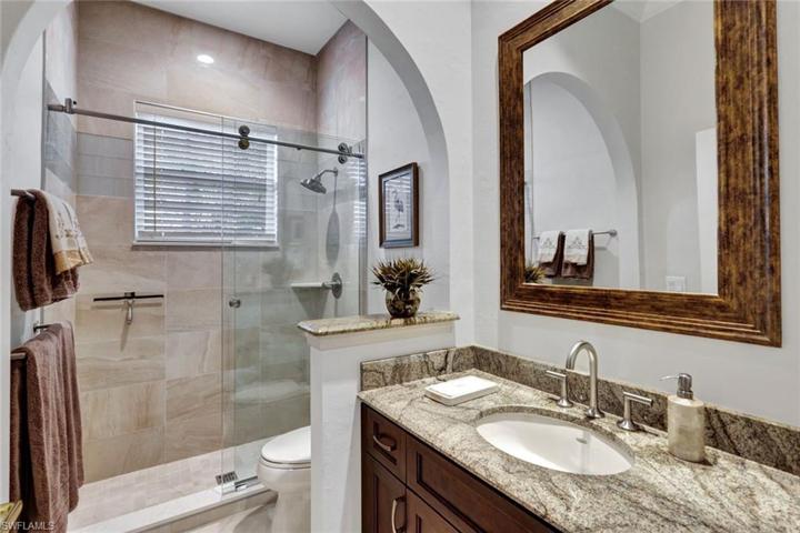 Large guest bath with walk-in shower in hallway across from den.