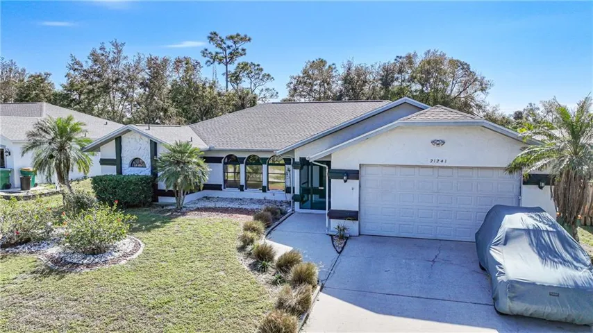 Ranch-style home featuring a garage and a front lawn