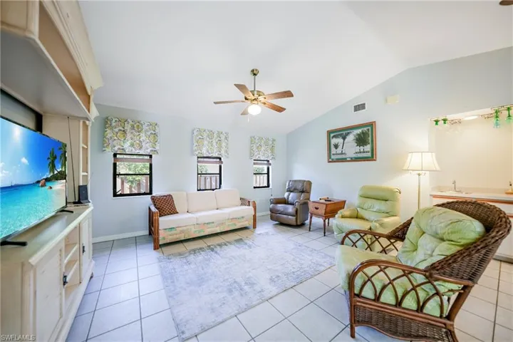 Living room featuring ceiling fan, light tile patterned floors, and lofted ceiling