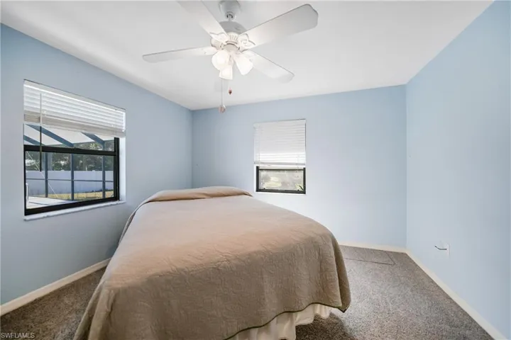 Bedroom with carpet flooring, multiple windows, and ceiling fan