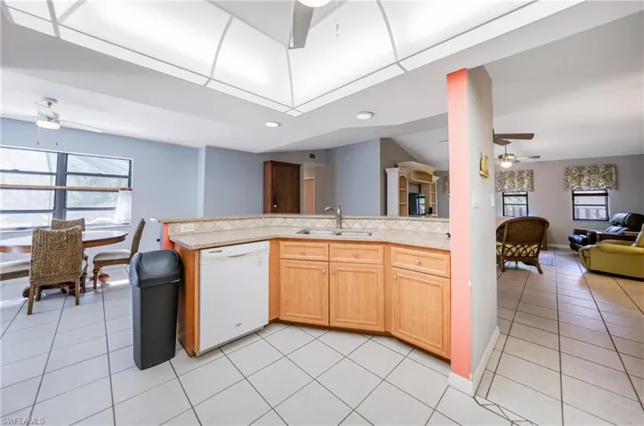 Kitchen featuring dishwasher, light tile patterned flooring, decorative backsplash, and sink