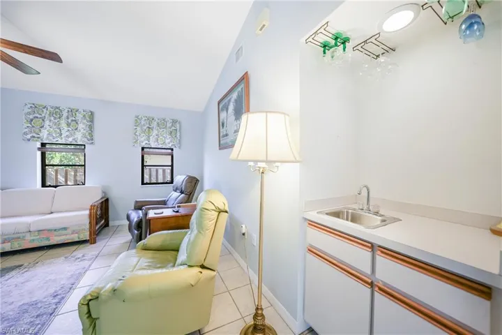 Tiled living room featuring ceiling fan, sink, and lofted ceiling