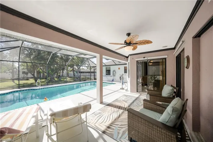 View of swimming pool featuring glass enclosure, ceiling fan, and a patio area