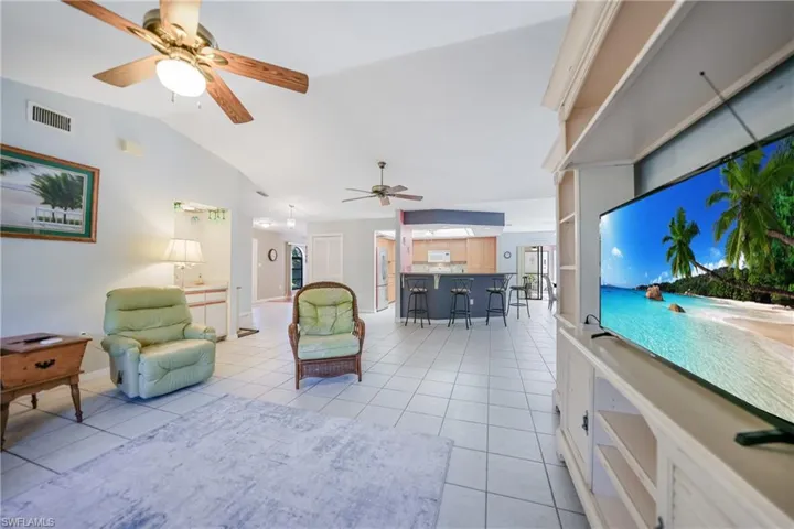 Tiled living room featuring ceiling fan and lofted ceiling