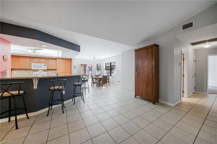Kitchen with ceiling fan, backsplash, kitchen peninsula, lofted ceiling, and a kitchen bar