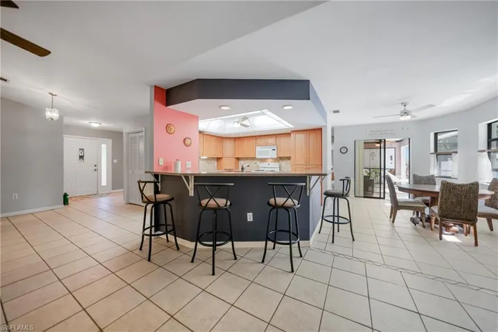 Kitchen featuring ceiling fan, decorative backsplash, light tile patterned floors, a kitchen bar, and kitchen peninsula