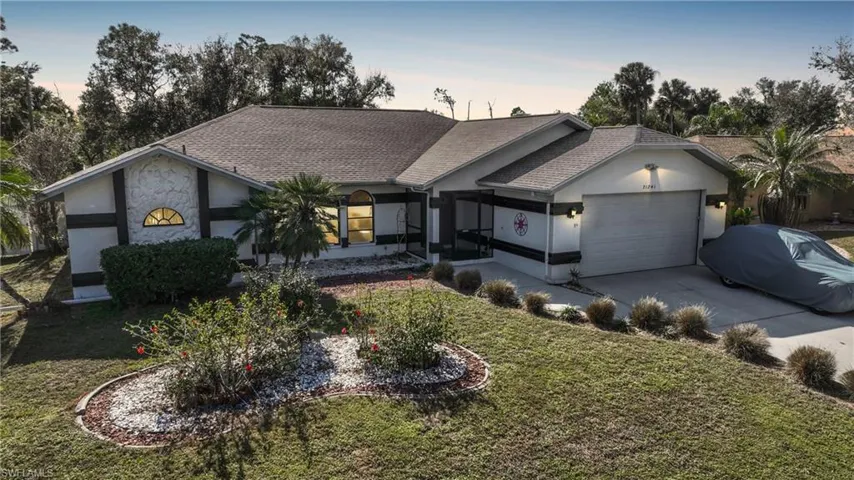 Ranch-style house featuring a lawn and a garage