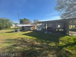 Back of property featuring a lawn and an outbuilding