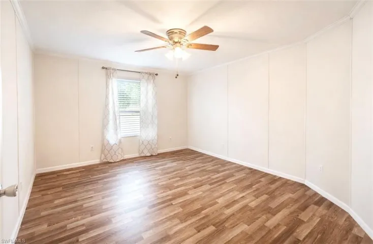 Spare room with wood finished floors, ceiling fan, and ornamental molding