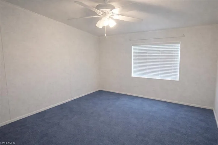 Empty room featuring a ceiling fan and carpet floors