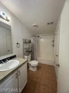 Bathroom featuring vanity, shower / bathtub combination with curtain, and a textured ceiling