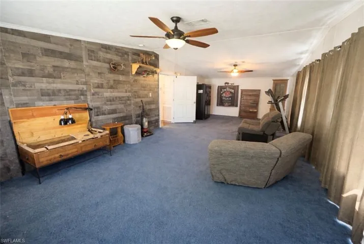 Oversized living room with wooden walls, vaulted ceiling, and a ceiling fan