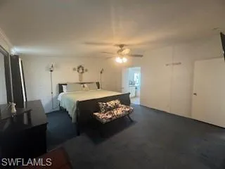 Bedroom with a ceiling fan and dark colored carpet