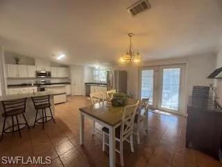Dining area featuring hanging lights, french doors, and a textured ceiling