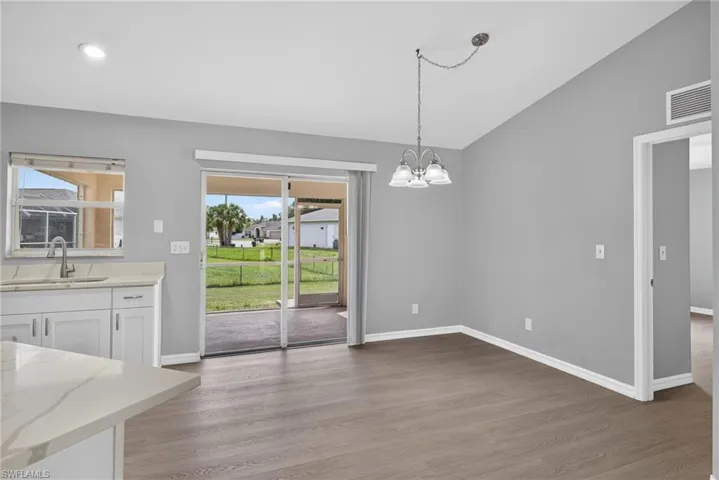 Dining room with kitchen to left, slider to lanai in middle, and minor bedrooms to the right