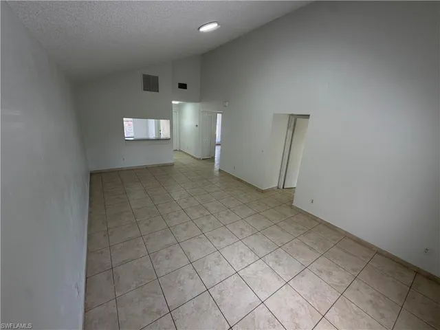 Spare room featuring light tile patterned floors and a high textured ceiling