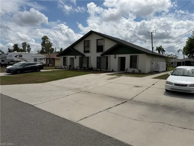 View of front of house with stucco siding, a front yard, and driveway