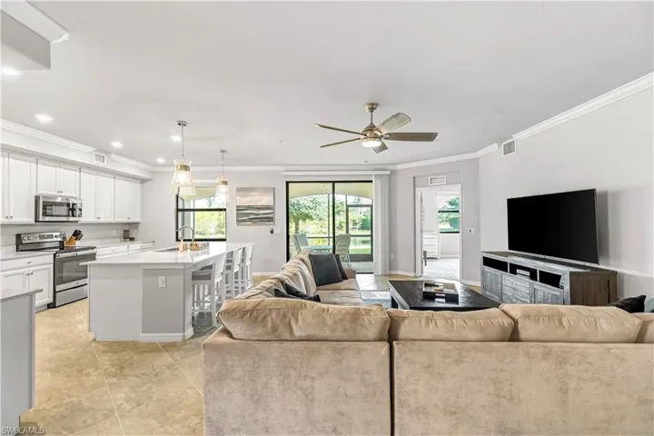 Living room with ornamental molding, a ceiling fan, and light tile patterned floors
