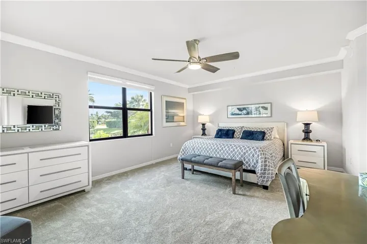 Bedroom with ornamental molding, light colored carpet, and a ceiling fan
