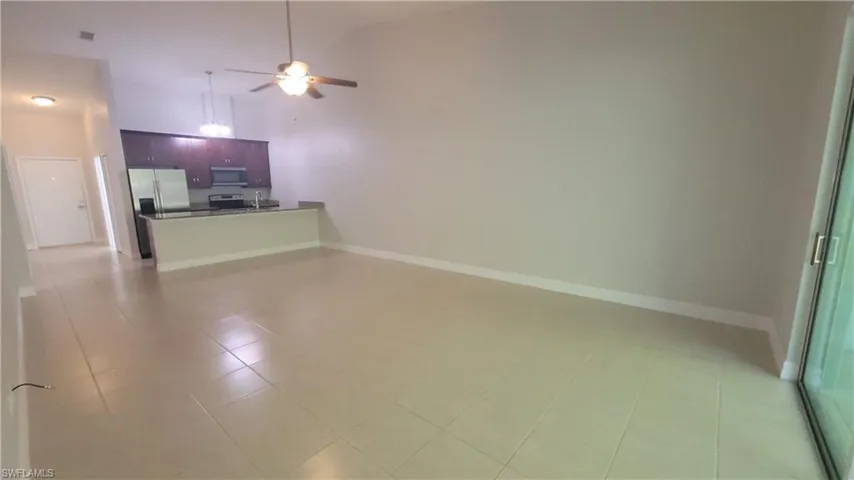 Unfurnished living room with ceiling fan, high vaulted ceiling, and light tile patterned floors