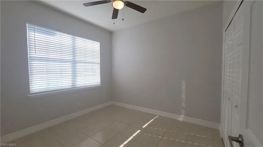 Guest bedroom with ceiling fan and light tile patterned floors