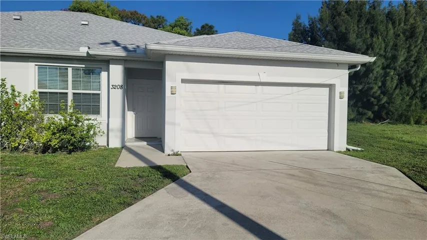 Ranch-style house featuring a shingled roof, concrete driveway, an attached garage, and a front yard