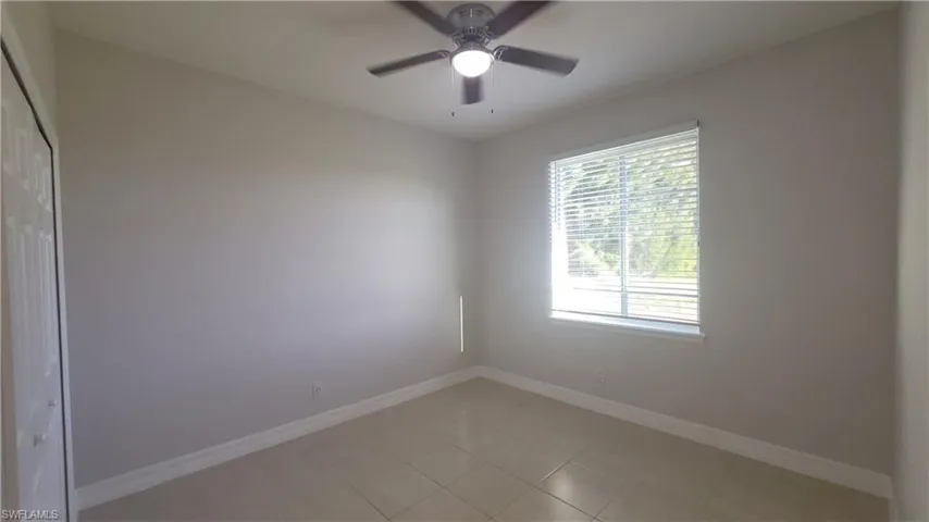 Guest bedroom with light tile patterned flooring and a ceiling fan