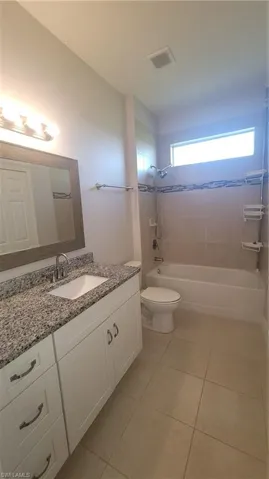 Guest bathroom with vanity, tile patterned flooring, and shower / bath combination