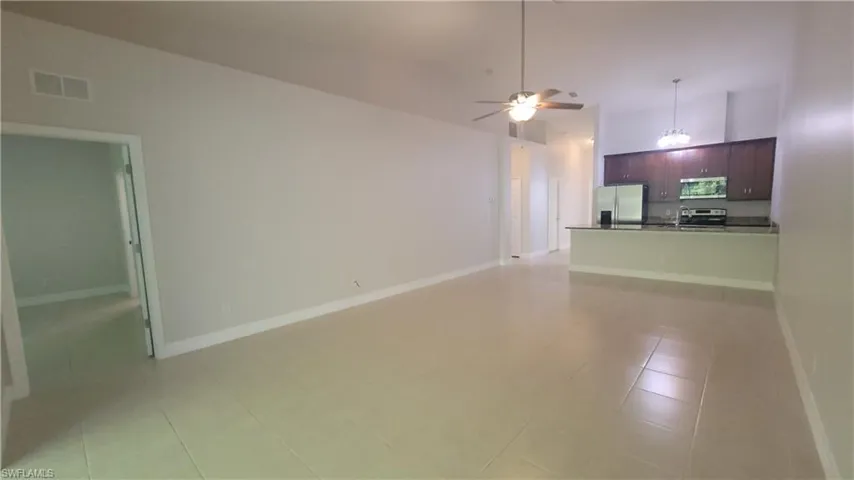 Unfurnished living room with a high ceiling, ceiling fan, and light tile patterned floors