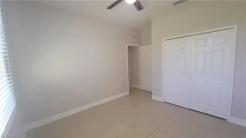 Guest bedroom featuring light tile patterned floors, a closet, and a ceiling fan